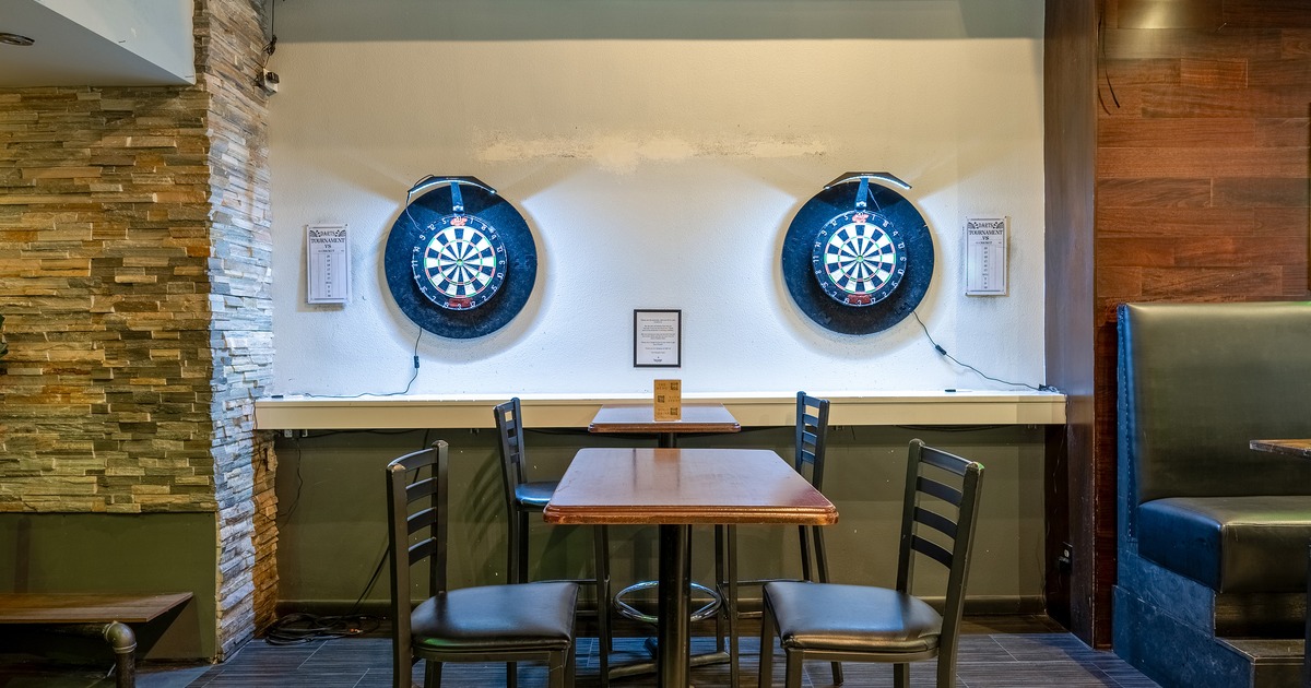 Sports bar interior space, tall bar stools and high tables and two electronic dartboards on the wall