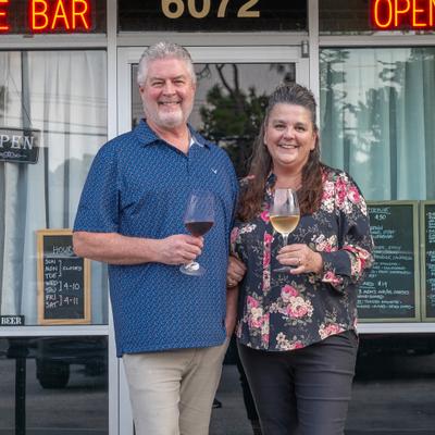 Two people standing outside holding wine glasses.