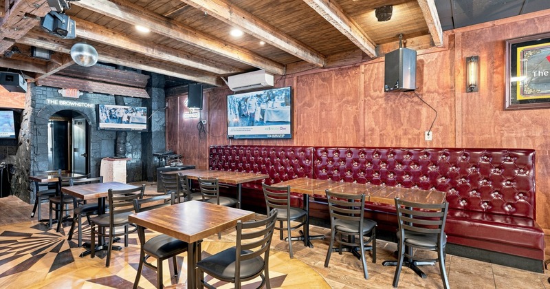 Interior with  red leather seating, wooden tables, and ceiling beams, with televisions on the walls.