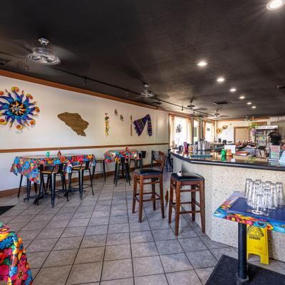 Restaurant interior featuring bar seating, high-top tables, and wall decor.