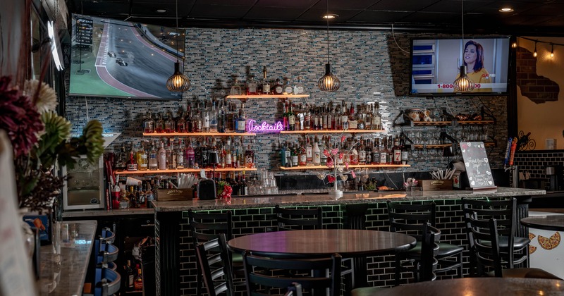 Bar area featuring a well-stocked liquor bar with shelving and hanging lights