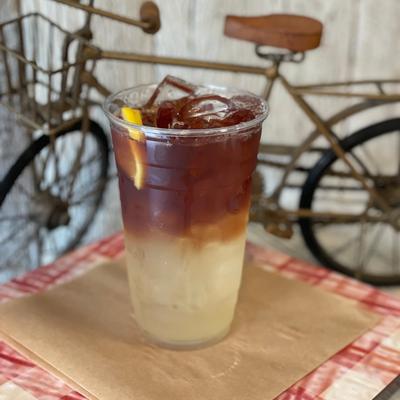 Iced tea and lemonade mix in a plastic cup with a slice of lemon.