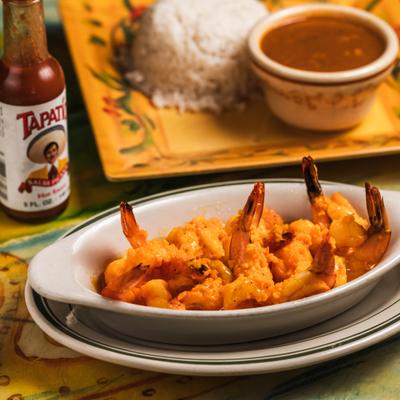 Shrimp in garlic sauce served with sides of rice and beans and a bottle of beer.