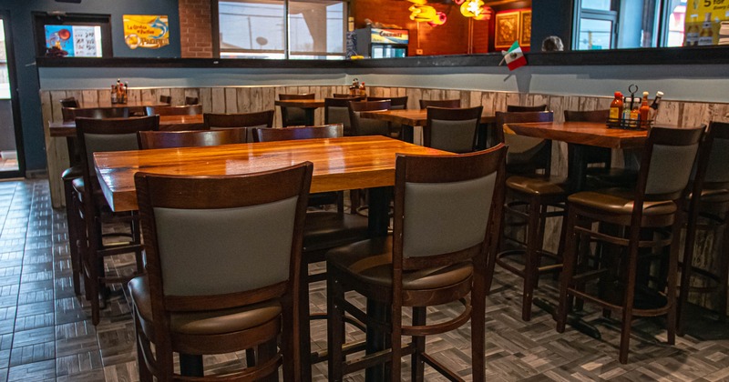 Interior of a restaurant with wooden tables and high chairs on a tiled floor