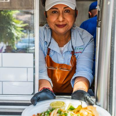 Person serving a plate of food from a truck.