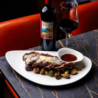 Grilled steak dish plate served on a table with red wine.