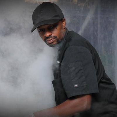 A cook in action surrounded by cooking smoke