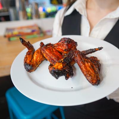 Plate of glazed chicken wings held by a server.