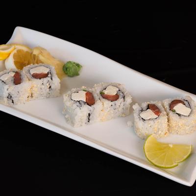 Sushi rolls with tuna and cream cheese on a plate with wasabi sauce and citrus.