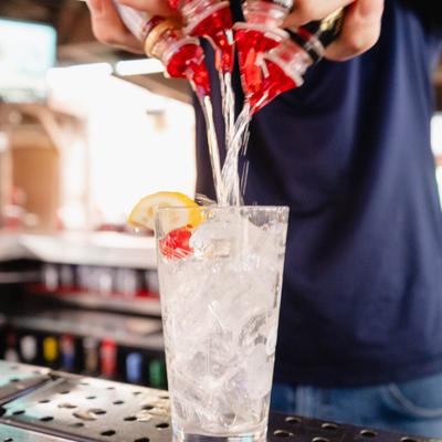 Bartender mixing a cocktail by pouring drinks into an ice-filled glass.