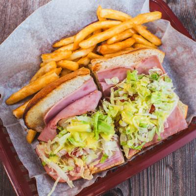 Ham and cheese sandwich with shredded lettuce and fries.
