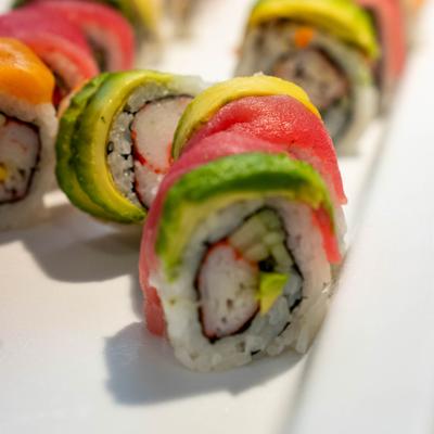 A close-up of a colorful rainbow sushi roll with shrimp tempura inside.