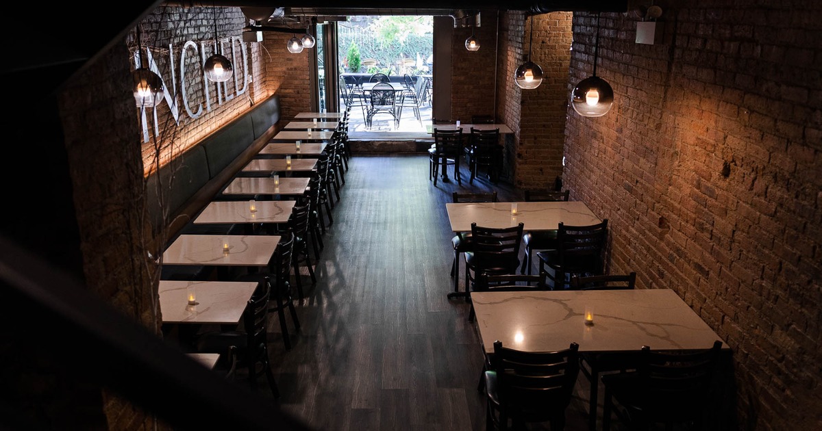 Interior, lined up dining tables with banquette seating by a wall, tables and chairs