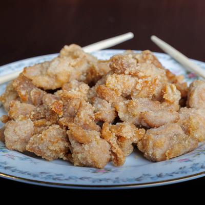 Crispy fried chicken bites served on a decorative plate with chopsticks in the background.