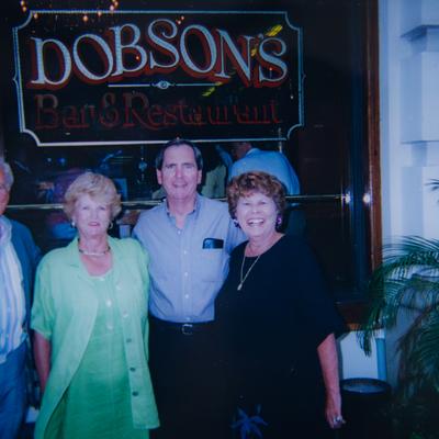 Four people posing in front of the Dobson's Bar and Restaurant sign