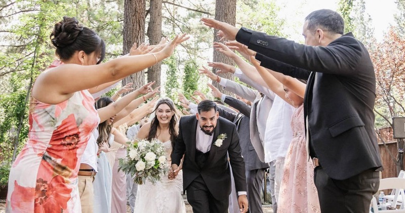 Bride and groom walking through an archway of hands