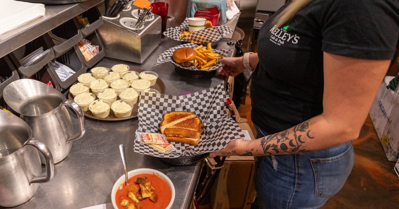 A person in the kitchen holding trays of food