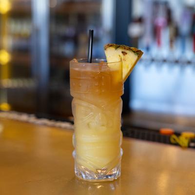 Cocktail in a tikki glass garnished with a slice of pineapple.