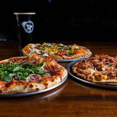 Prosciutto Special, Bourbon BBQ Chicken and Buffalo Chicken pizza arranged on a table.