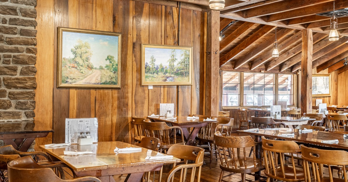 A rustic interior with wooden tables and chairs, decorative paintings on the wall