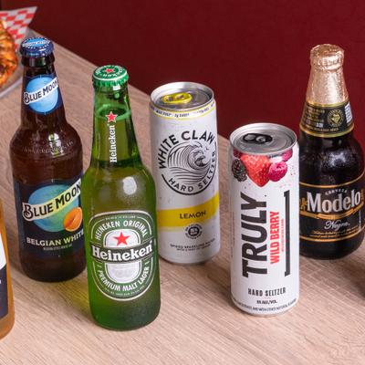 Beer bottles and hard seltzer cans on a wooden table.