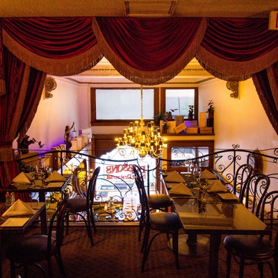 Elegant restaurant dining area with ornate curtains and chandelier.