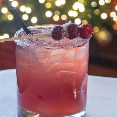 Festive red cocktail with sugared cranberries on a skewer and a sugary rim.