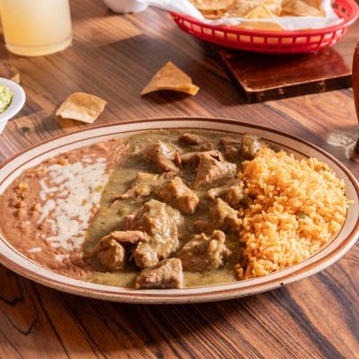 Pork chunks in green sauce, served with rice, and refried beans.