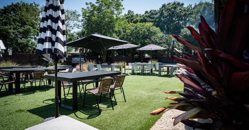 Exterior, partially covered seating area, tables with chairs, parasols, grass flooring