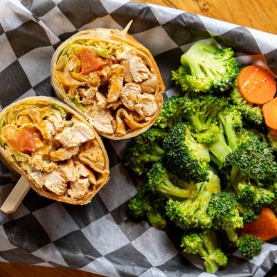 Creek sauce chicken tender wrap served with broccoli and carrots on the side.