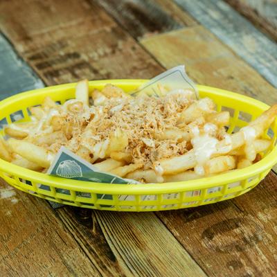 Loaded fries in a yellow basket on a wooden table.