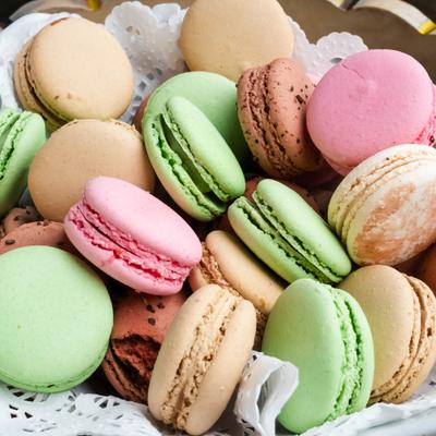 Colorful macarons in a white basket - pastel shades of pink, green, beige & brown..