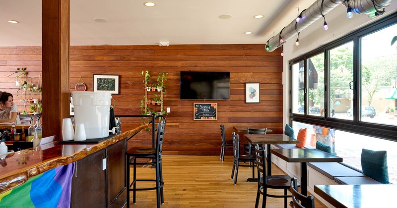 Interior, seating area, bar with stools on the left, banquette bench with tables and chairs