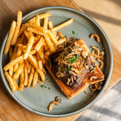 Steak topped with crispy onions, served on garlic toast with fries.