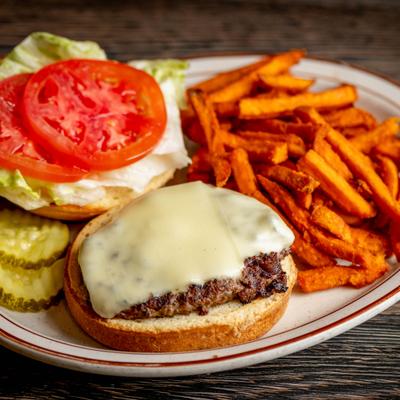 Open faced cheeseburger alongside sweet potato fries.