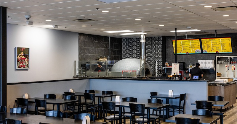 Interior space, dining area, order counter and open kitchen with wood fire pizza oven