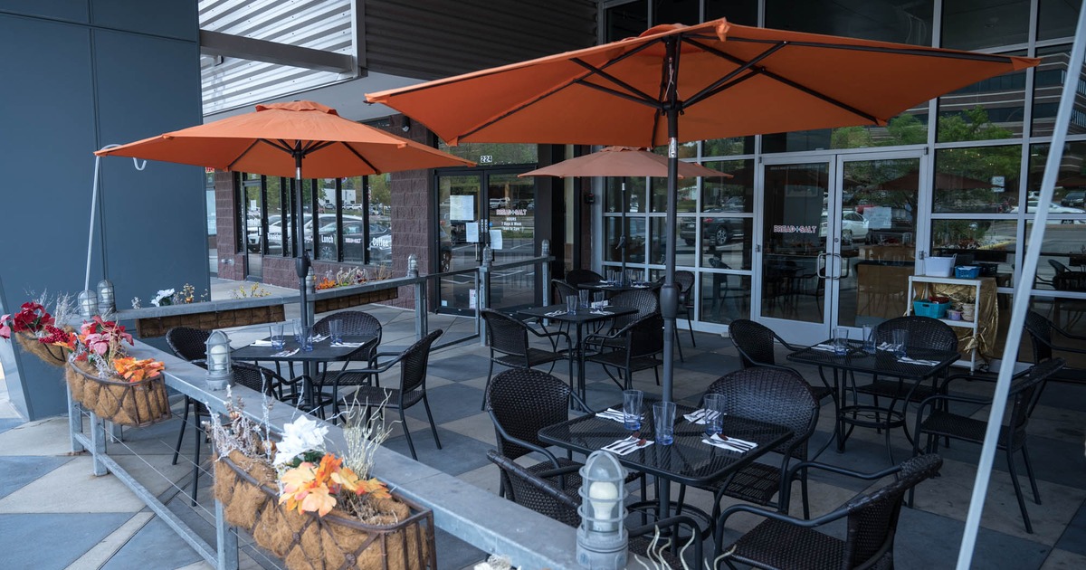 Exterior, patio, covered seating area, tables and chairs under parasols, metal railing