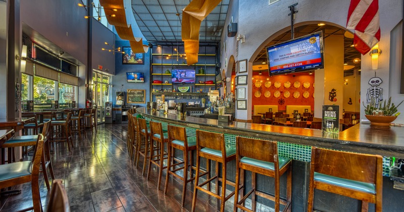 Restaurant bar interior with wooden bar stools, ceiling decorations, and flat-screen TVs