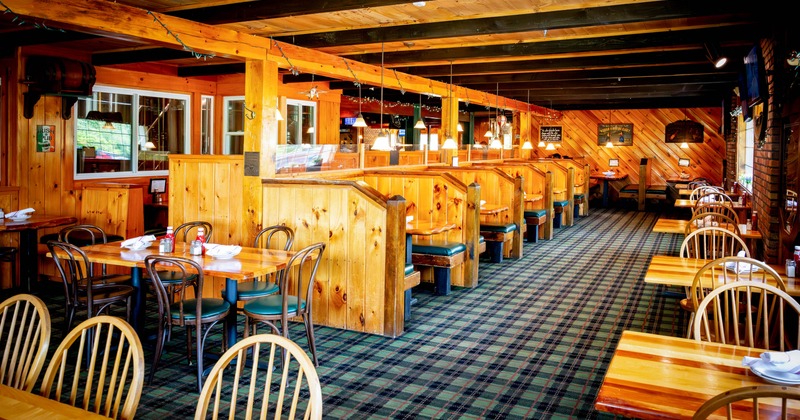 Interior, wooden booths and tables, featuring warm lighting and plaid carpet