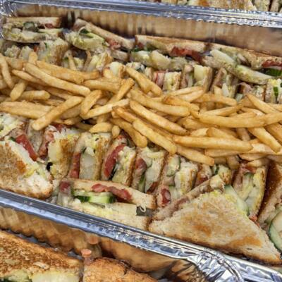 A catering tray of sandwiches and fries.