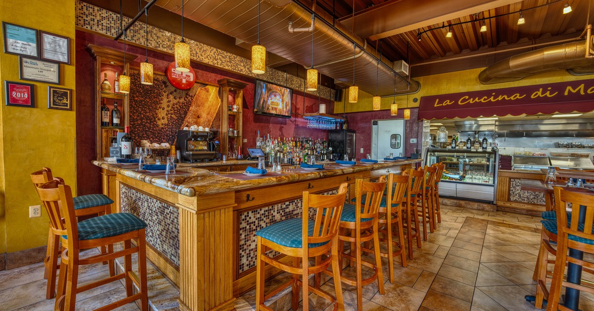Restaurant interior with a wooden bar, pendant lights and mosaic decor.