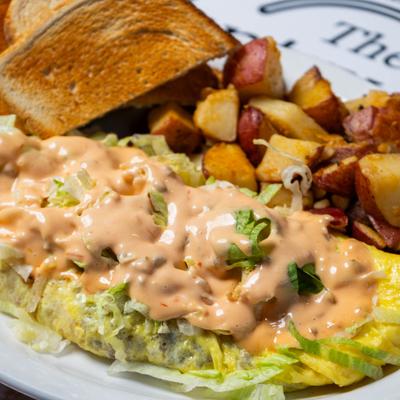 Omelet with lettuce, Thousand Island dressing, potatoes, and toast.