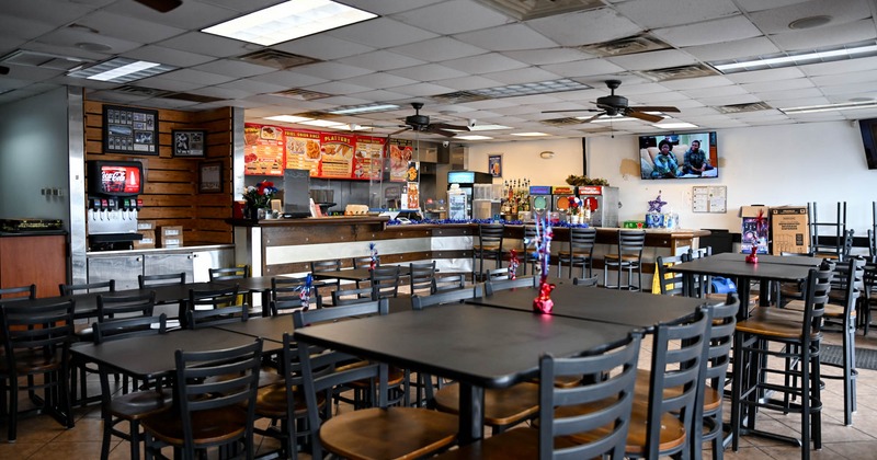 Interior, high and regular seating area, tables with chairs, kitchen and checkout counter