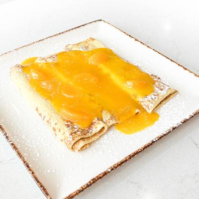 Crepes topped with orange sauce.