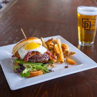 Burger with bacon, lettuce, tomato, fried egg, fries and a glass of beer photo.