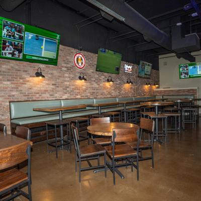 Interior, seating area with exposed brick walls and multiple TVs showing sports.