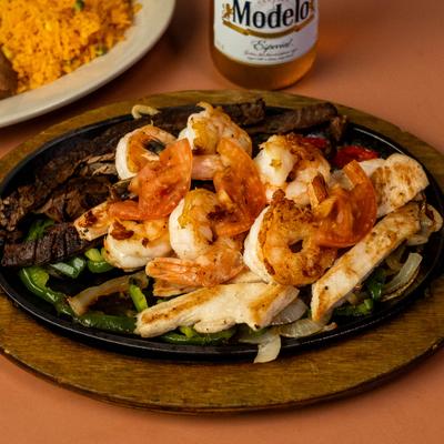 Mixed Fajitas skillet with shrimp, chicken, steak, and grilled vegetables.