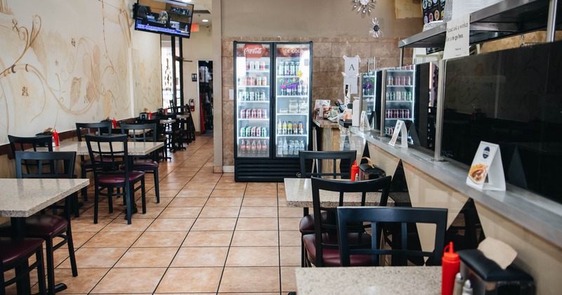 Interior, tables ready for guests, fridge with canned and bottled drinks in the back