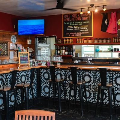 Wooden bar counter with a black and white geometric tile pattern and a chalkboard menu.