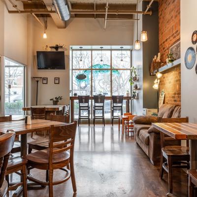 Interior with wooden tables, pendant lights, large windows, and a TV.